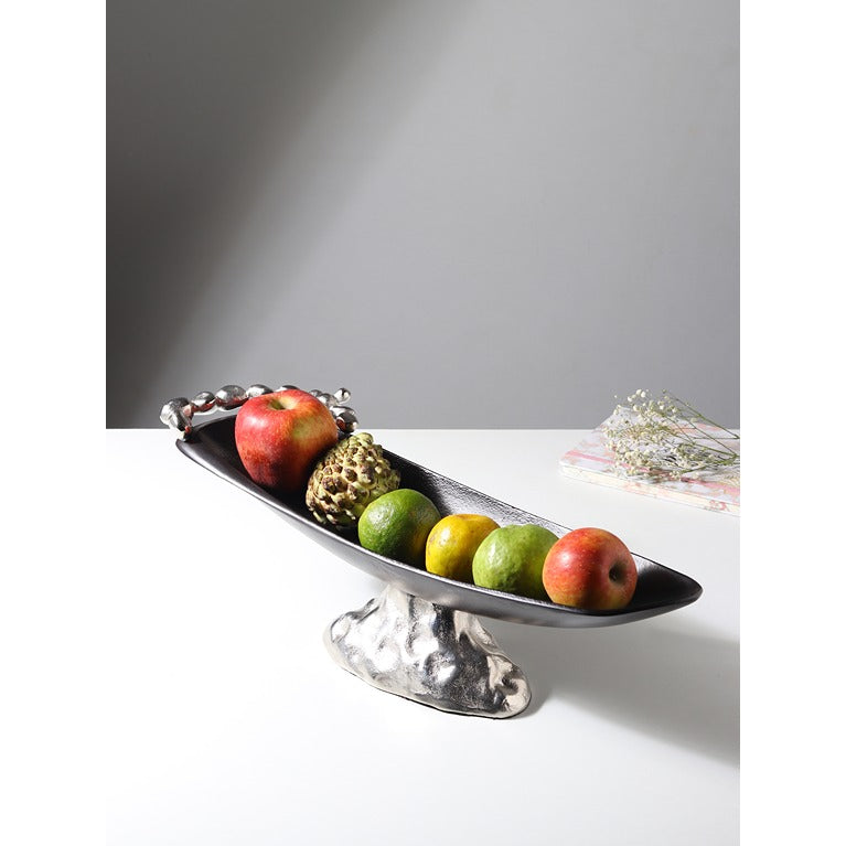 Decorative silver fruit bowl with fruits on a white surface