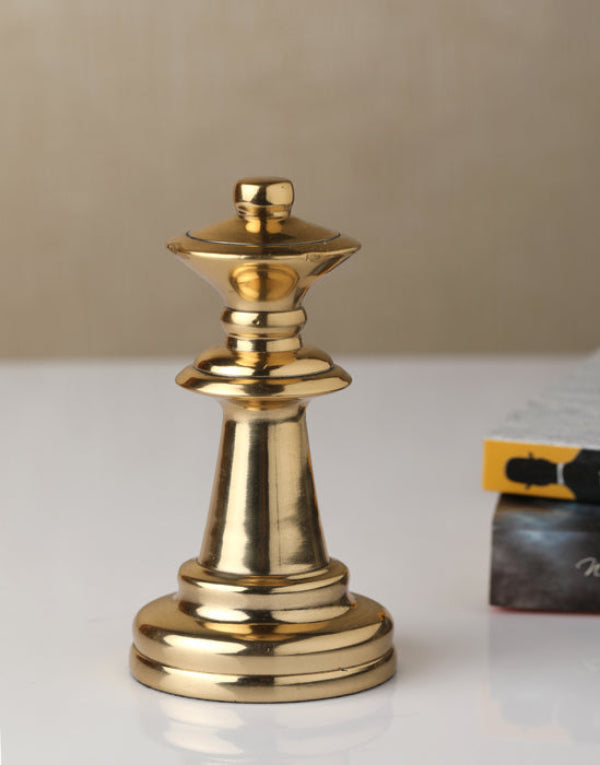 Gold chess piece on a surface with a blurred book in the background