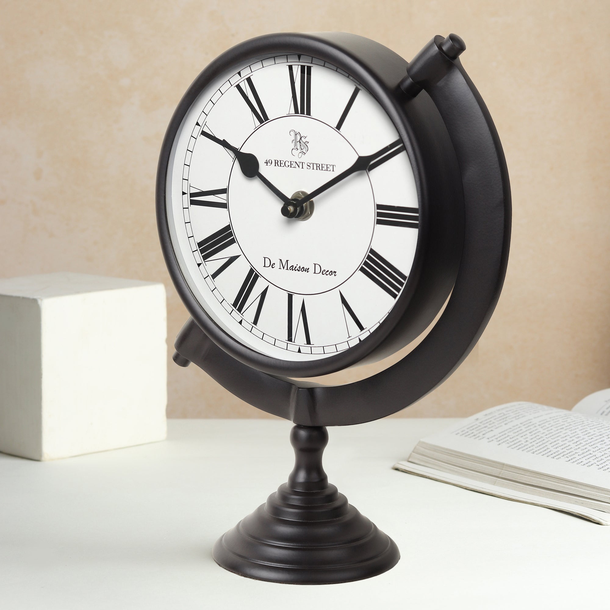 Black table clock with white face and Roman numerals on a beige background