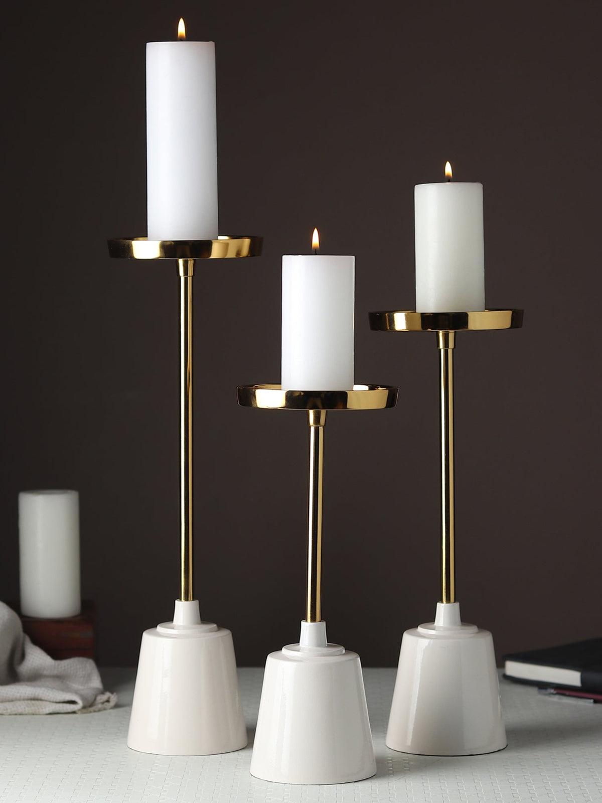 Three candle holders with white candles on a dark background